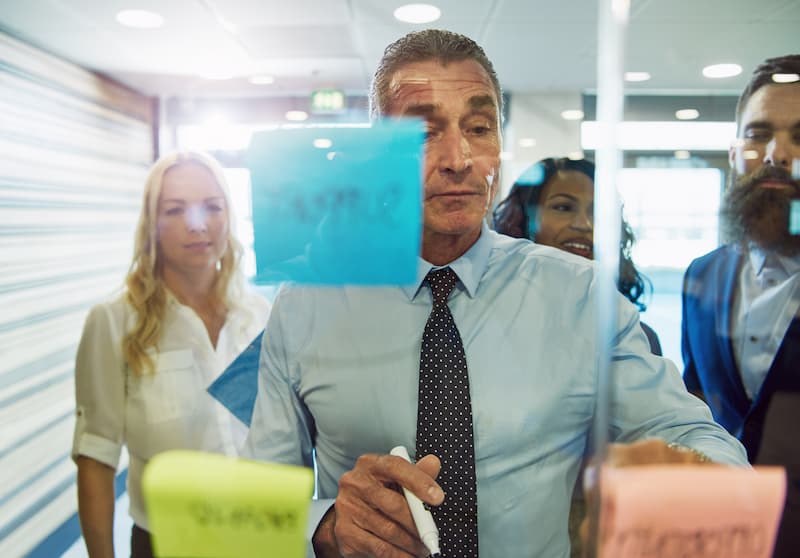 businessman-looking-at-sticky-notes-on-glass-2021-08-27-11-10-39-utc-op