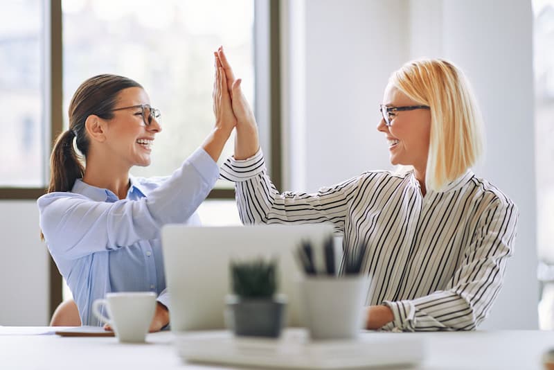 two-smiling-businesswomen-high-fiving-together-in-2021-08-27-11-10-39-utc-op